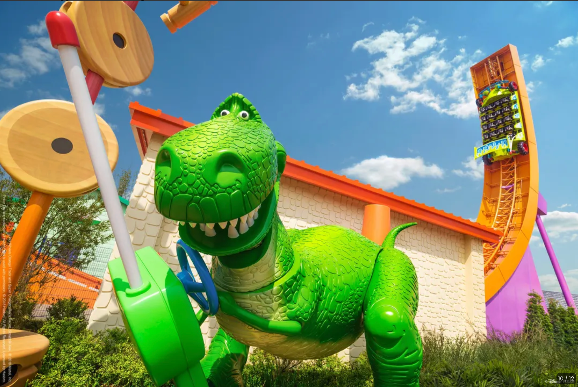 Large green Rex dinosaur statue from Toy Story at Shanghai Disneyland with colorful playground equipment and blue sky in background