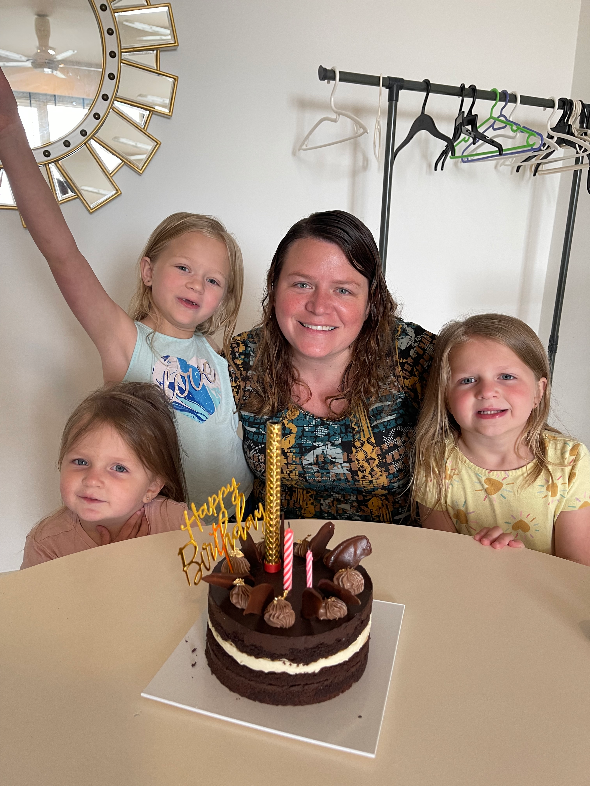 Lindsay and the three girls posing in front of a birthday cake in a Malaysia Airbnb