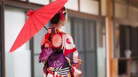 Woman in traditional colorful kimono holding red parasol in Japanese setting